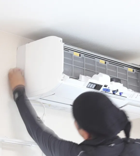 エアコン移設や電気工事の専門業者が壁面の室内機カバーを取り外して内部の配線や部品を慎重に点検し効率的に作業を進めている瞬間